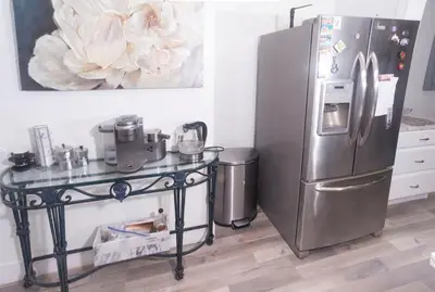 a kitchen with a table and a stainless steel refrigerator at Blanquitas Home in Long Beach