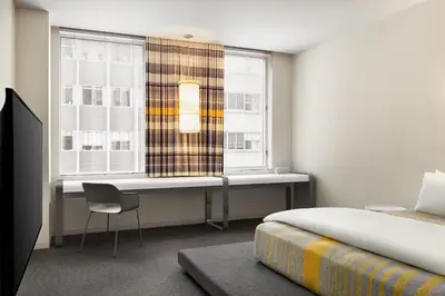 a bedroom with a bed and a desk and a window at The Delphi Downtown LA in Los Angeles