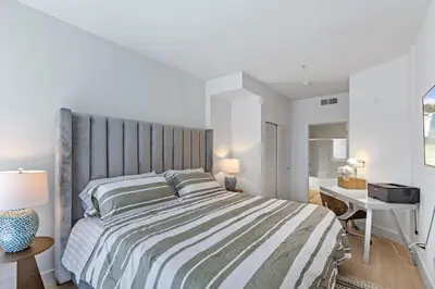 a white bedroom with a large bed and a desk at 1 Luxury Apartment in Los Angeles