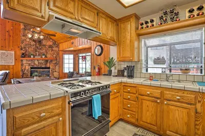 a kitchen with wooden cabinets and a stove top oven at A-Frame Cali Cabin with Unobstructed Valley Views! in Running Springs