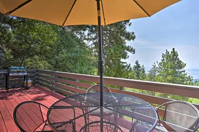 a table and chairs under an umbrella on a deck at A-Frame Cali Cabin with Unobstructed Valley Views! in Running Springs