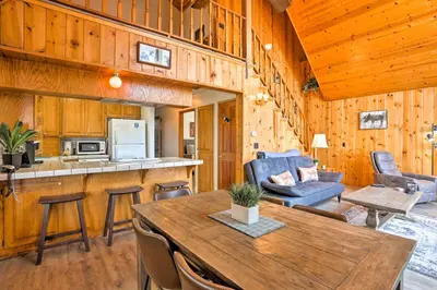 a living room with a table and a kitchen at A-Frame Cali Cabin with Unobstructed Valley Views! in Running Springs