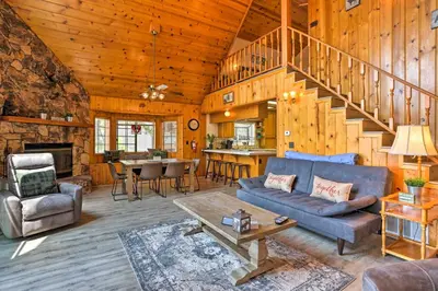 a living room with a couch and a staircase at A-Frame Cali Cabin with Unobstructed Valley Views! in Running Springs