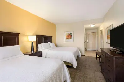 a hotel room with two beds and a flat screen tv at Hampton Inn & Suites San Bernardino in San Bernardino