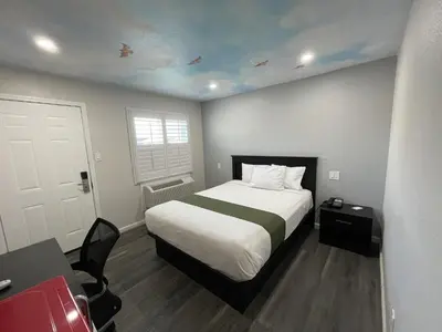 a bedroom with a bed and a desk and a door at Fontana Inn in Fontana