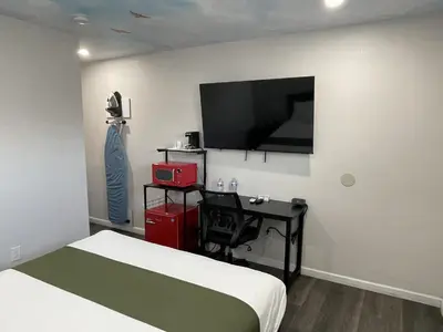 a bedroom with a bed and a desk and a tv at Fontana Inn in Fontana