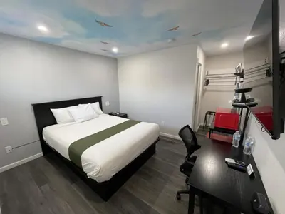 a hotel room with a bed and a desk and a desk at Fontana Inn in Fontana