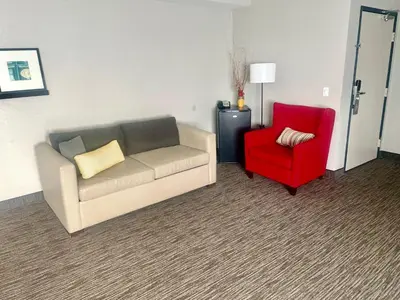 a living room with a couch and a red chair at Country Inn & Suites by Radisson, Bakersfield, CA in Bakersfield