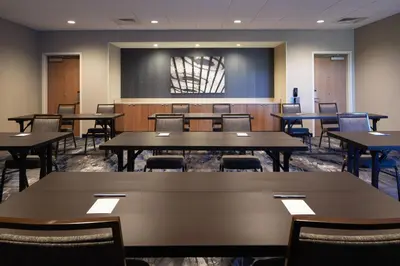 a conference room with tables and chairs and a screen at Fairfield by Marriott Inn & Suites Palmdale West in Palmdale