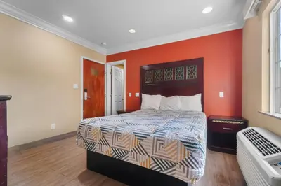 a bedroom with a bed with an orange wall at Santa Fe Inn Los Angeles in Huntington Park