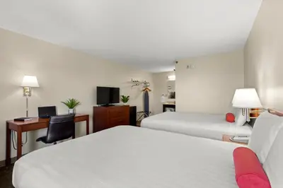 a hotel room with two beds and a desk at Good Nite Inn Buena Park in Buena Park