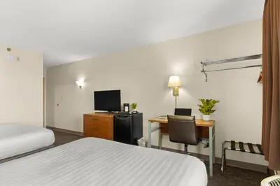 a hotel room with a bed and a desk with a computer at Good Nite Inn Buena Park in Buena Park