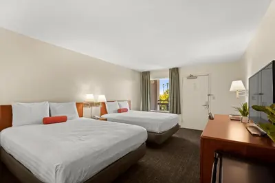 a hotel room with two beds and a desk at Good Nite Inn Buena Park in Buena Park