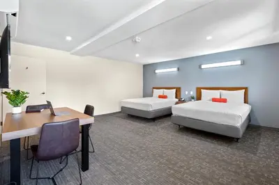 a room with two beds and a desk and a table at Good Nite Inn Calabasas in Calabasas