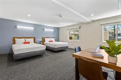 a hotel room with two beds and a desk and a desk at Good Nite Inn Calabasas in Calabasas