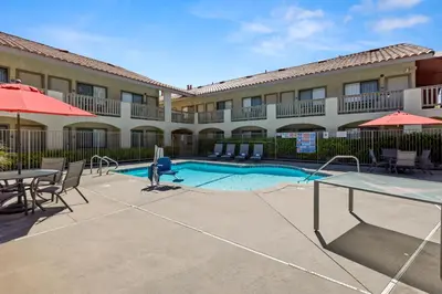 a pool at a hotel with tables and umbrellas at Good Nite Inn Camarillo in Camarillo