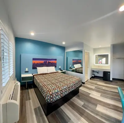a bedroom with a bed and a blue wall at La Casa Motel, Los Angeles - Burbank Airport in Sun Valley