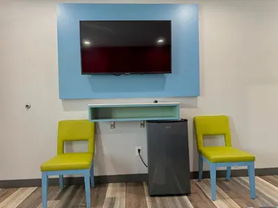 two yellow chairs and a tv in a waiting room at La Casa Motel, Los Angeles - Burbank Airport in Sun Valley