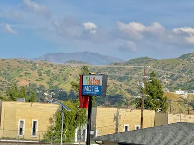 a sign for a hotel motel with mountains in the background at La Casa Motel, Los Angeles - Burbank Airport in Sun Valley