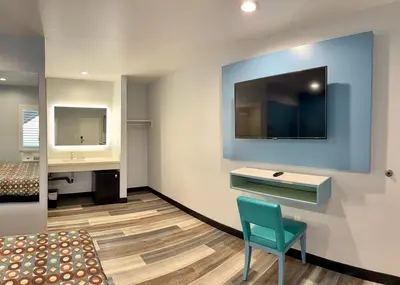 a room with a desk and a tv on a wall at La Casa Motel, Los Angeles - Burbank Airport in Sun Valley