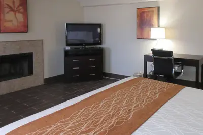 a hotel room with a bed and a tv and a fireplace at Comfort Inn & Suites Mojave in Mojave