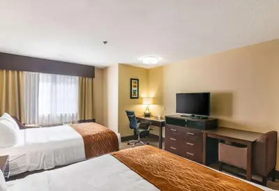 a hotel room with two beds and a desk with a television at Comfort Inn & Suites Mojave in Mojave