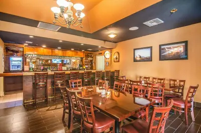 a restaurant with wooden tables and chairs and a bar at Comfort Inn & Suites Mojave in Mojave