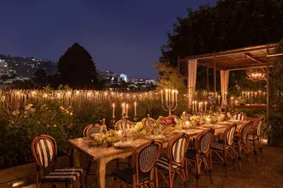 a long table with chairs and lights at night at Petit Ermitage in Los Angeles