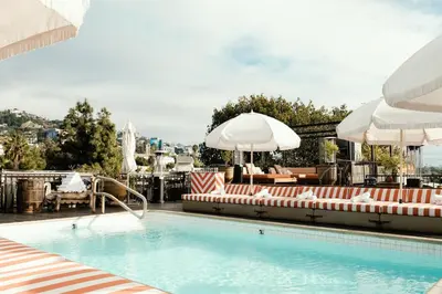 a swimming pool with lounge chairs and umbrellas at Petit Ermitage in Los Angeles