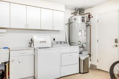 a kitchen with white cabinets and a washer and dryer at Seaside Getaway in Oxnard