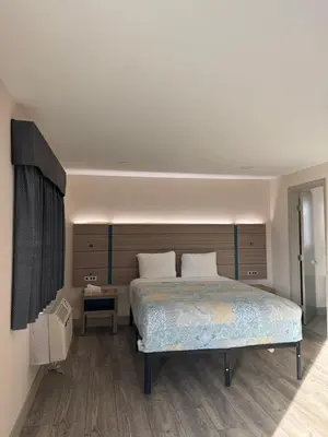 a bedroom with a large bed with a wooden headboard at Rodeway Inn Ventura Midtown in Ventura