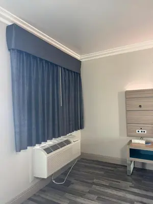 a room with a radiator and a window with blue curtains at Rodeway Inn Ventura Midtown in Ventura