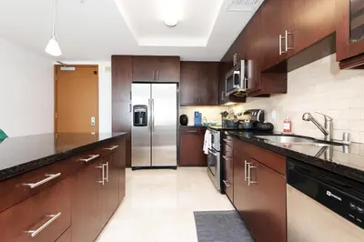a kitchen with wooden cabinets and a stainless steel refrigerator at Sky-Rise Apartments in Los Angeles