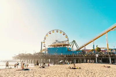 a beach with a ferris wheel and people on the beach at Sky-Rise Apartments in Los Angeles