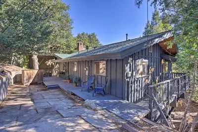 a tiny house in the woods with a porch at Modern and Unique Cabin with Deck by Lake Gregory! in Crestline