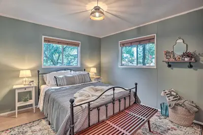 a bedroom with a bed and two windows at Modern and Unique Cabin with Deck by Lake Gregory! in Crestline