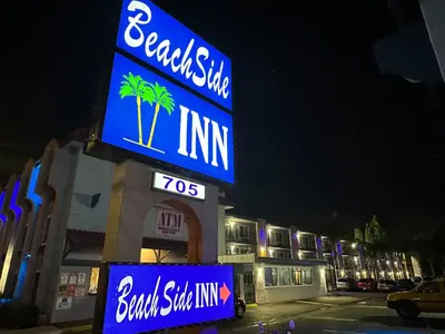 a sign for a building with palm trees on it at Beachside Inn in Anaheim