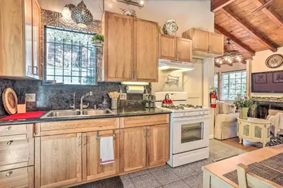 a kitchen with wooden cabinets and white appliances at 1 Mi to Lake Gregory Boho Crestline Cabin in Crestline