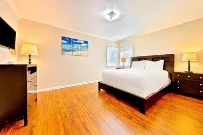 a bedroom with a large white bed and a television at Disney Getaway in Anaheim