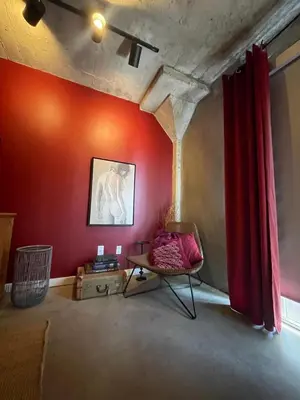 a living room with a red wall and a chair at BO-BOU Suite in Los Angeles