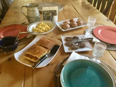 a wooden table with plates of food on it at The Old Bear BnB in Pine Mountain Club