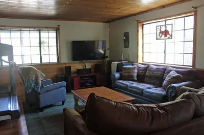 a living room with couches and a table and windows at The Old Bear BnB in Pine Mountain Club