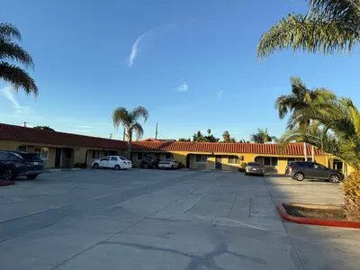 a hotel with cars parked in a parking lot at Rocky Inn Motel Long Beach, CA in Long Beach
