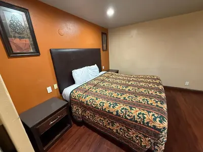 a small bedroom with a bed and a table at Rocky Inn Motel Long Beach, CA in Long Beach