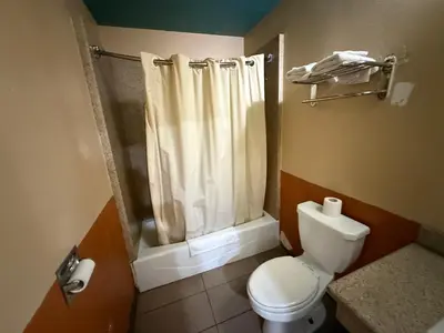 a bathroom with a toilet and a shower curtain at Rocky Inn Motel Long Beach, CA in Long Beach