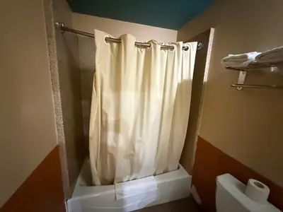 a bathroom with a shower curtain and a toilet at Rocky Inn Motel Long Beach, CA in Long Beach