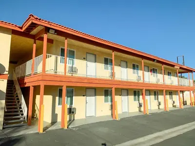 an apartment building with a staircase in a parking lot at Mojave Inn in Victorville