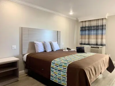 a bedroom with a large bed with a laptop on it at Mojave Inn in Victorville