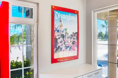 a poster of disneyland on a wall in a room with windows at Hotel 414 Anaheim in Anaheim