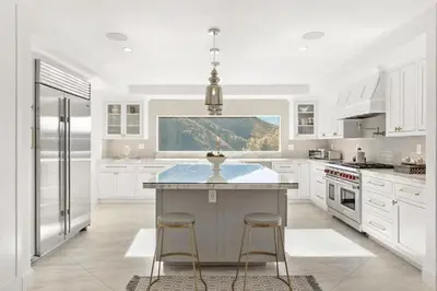 a white kitchen with a large island with two bar stools at Beverly Hills Maison in Beverly Hills